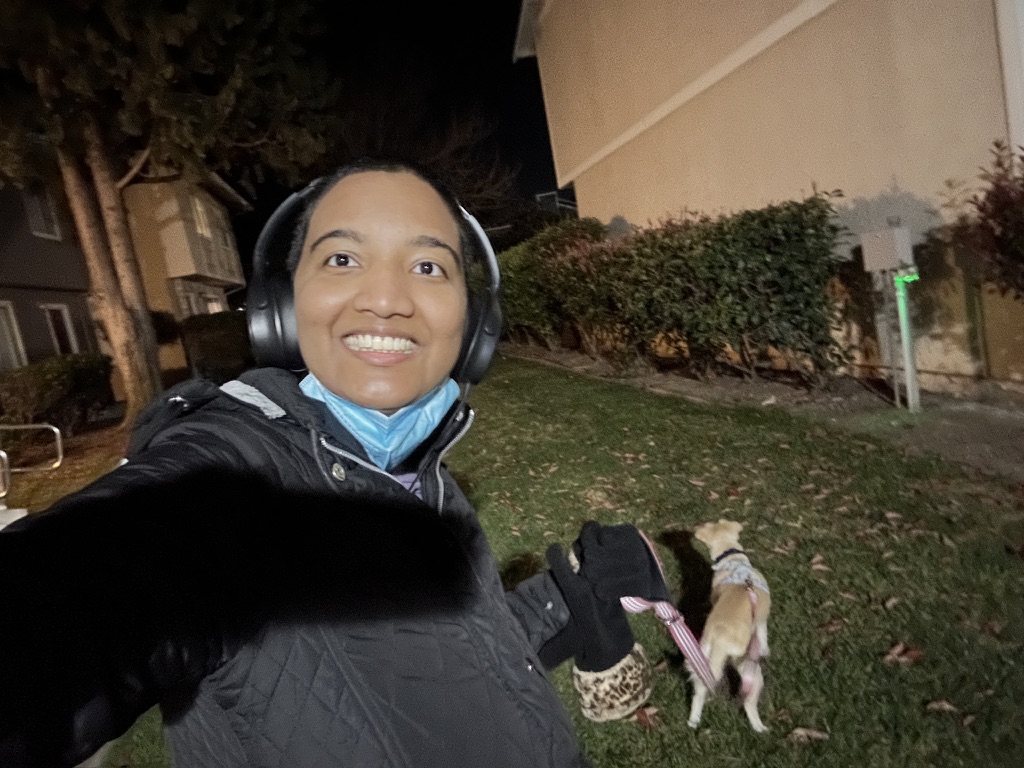 Harshini smiling during a nighttime walk with her dog Toffee in a quiet residential neighborhood.
