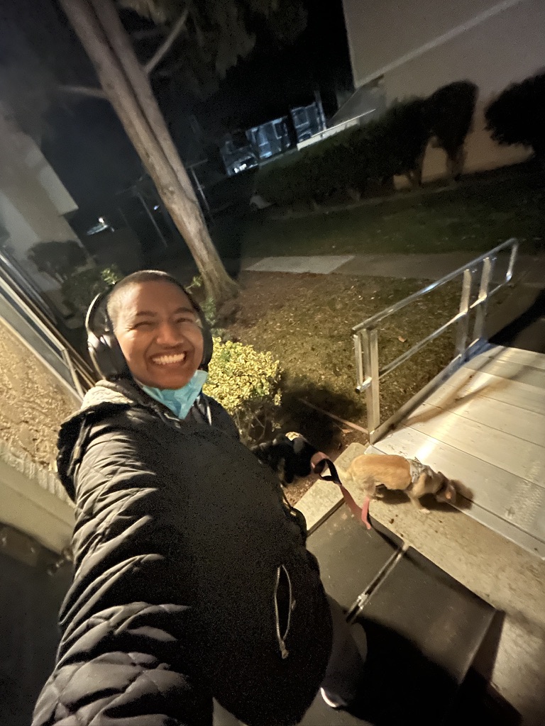 Harshini laughing while walking her dog Toffee down outdoor ramp during a nighttime neighborhood walk.