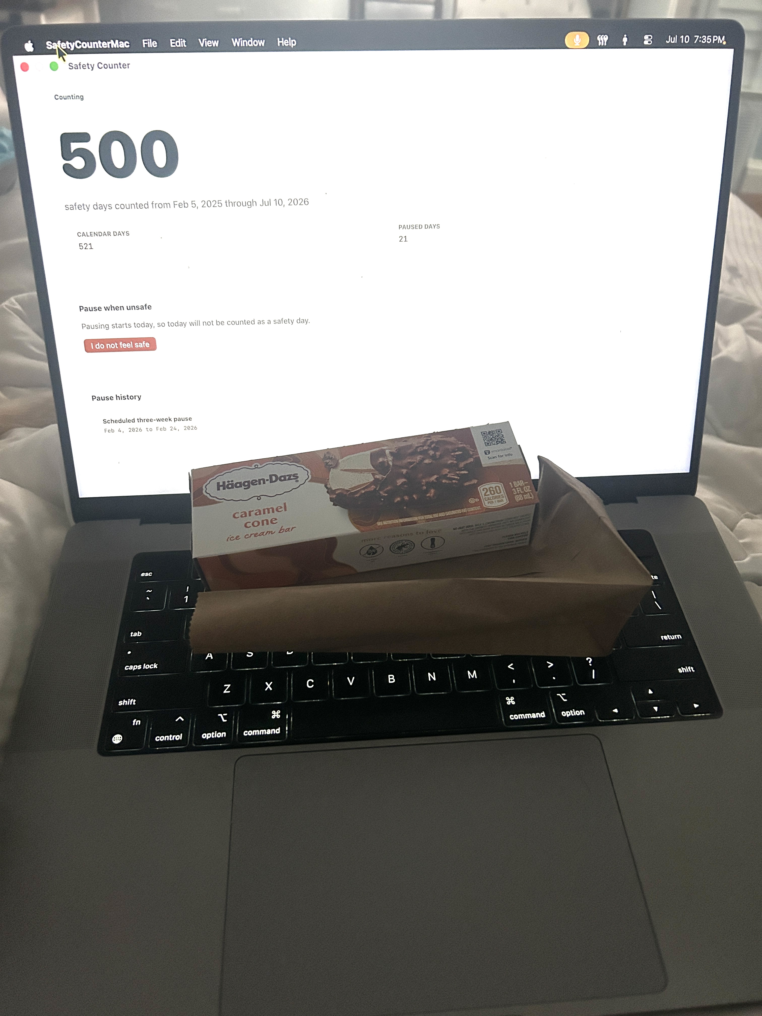 Laptop screen showing the Safety Counter app at 500 safety days, with an ice cream bar resting in front of the laptop on a bed.